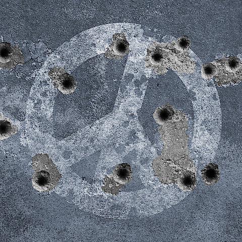 Peace symbol on a wall with bullet holes